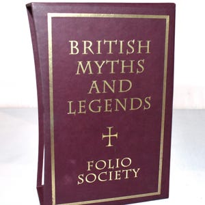 May include: A maroon book titled "British Myths and Legends" with gold lettering and a gold border. The Folio Society logo is at the bottom. The book is in a maroon slipcase.
