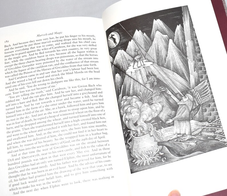 May include: An open book with text and a detailed black and white illustration. The illustration depicts a figure on a mountain peak, with other figures and a cauldron below. The page number 152 is visible.