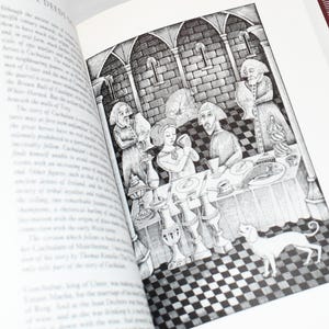 May include: An open book with a black and white illustration depicting a medieval scene. The image shows figures around a table, a dog, and architectural details. The text "THE DEEDS OF" is visible at the top of the page.