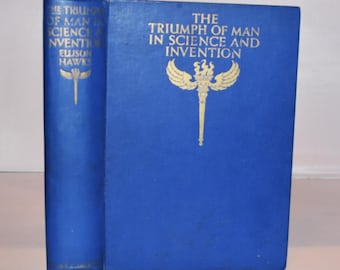 May include: A vintage hardcover book titled "The Triumph of Man in Science and Invention." The book has a blue cover with gold lettering and a gold emblem. The spine also features gold lettering and a similar emblem.