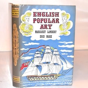 以下が含まれることがあります： マーガレット・ランバートとエニッド・マルクスによる「English Popular Art」というタイトルのヴィンテージ本。表紙には、帆船のイラストと2つの黄色と白の肖像画が描かれた青い空が描かれています。背表紙は金色の文字が入ったグレーです。