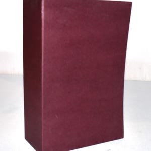 May include: A rectangular, burgundy-colored box with a slightly curved side. The box has a matte finish and is set against a white background. The box appears to be made of a sturdy material.
