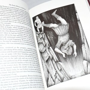 May include: An open book with a black and white illustration depicting a giant falling from a cliff. The illustration is detailed and shows a figure on top of the cliff. Text on the page describes the early history of Britain.