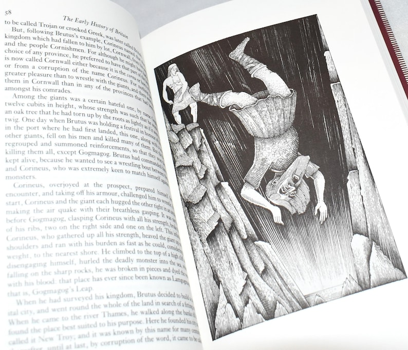 May include: An open book with a black and white illustration depicting a giant falling from a cliff. The illustration is detailed and shows a figure on top of the cliff. Text on the page describes the early history of Britain.