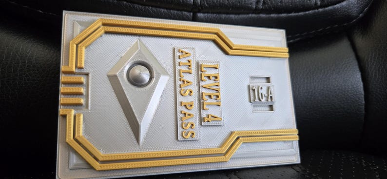 May include: A silver and gold metal key card with the text "LEVEL 4 ATLAS PASS" and "1G4" printed on it.