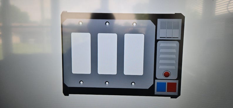 May include: A black and gray control panel with three white rectangular buttons. The panel has a silver faceplate with a series of small holes and a section with a red button and blue and red squares.