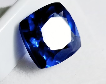 Può includere: Una pietra preziosa blu scuro con taglio a cuscino e un design sfaccettato.