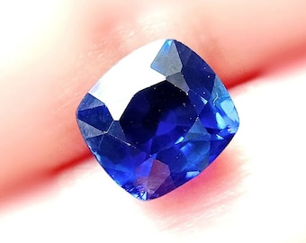 Può includere: Una pietra preziosa zaffiro blu scuro con taglio a cuscino. La pietra preziosa è sfaccettata e ha un'alta lucidatura.
