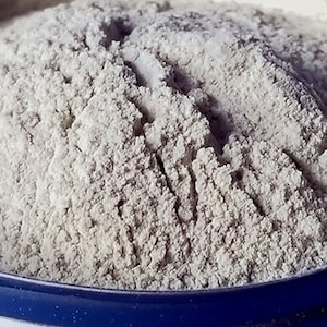 May include: A close-up of a white powder in a blue container. The powder is fine and smooth, and it appears to be a type of flour or baking powder.