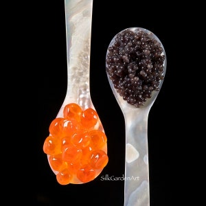 Puede incluir: Dos cucharas de nácar, una llena de huevas de color naranja brillante y la otra de caviar oscuro, sobre un fondo negro. Las cucharas son elegantes y las huevas y el caviar brillan.