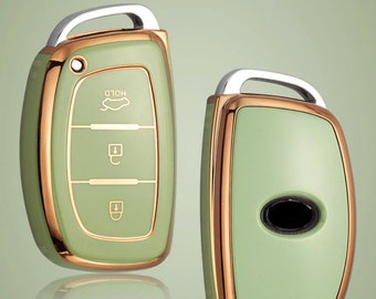 Könnte beinhalten: Ein grüner und goldener Autoschlüsselanhänger mit einem silbernen Ring. Der Schlüsselanhänger hat drei Knöpfe: "HOLD", "Entriegeln" und "Verriegeln".