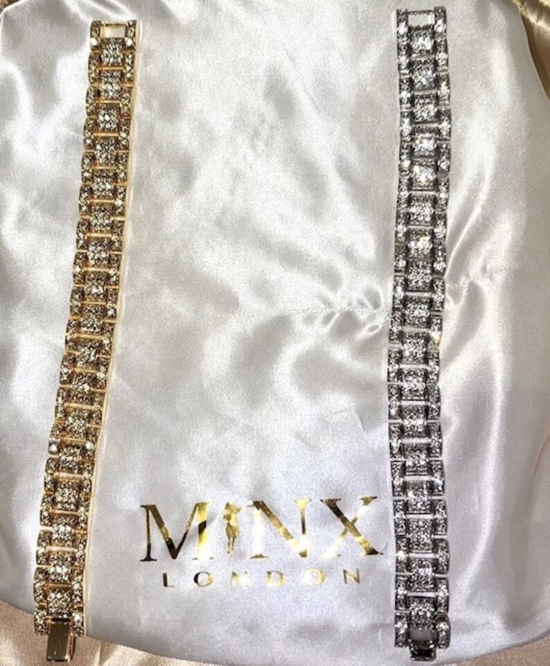 May include: Two rhinestone bracelets, one gold-toned and one silver-toned, are displayed on a white satin surface. The bracelets are rectangular with square-shaped rhinestones. The gold bracelet is on the left, and the silver bracelet is on the right.