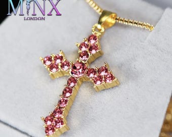 Op de afbeelding: Een gouden ketting met een hanger in de vorm van een roze kristallen kruis. Het kruis is gemaakt van kleine roze kristallen die in goudmetaal zijn gezet.