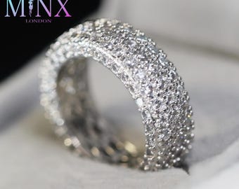 May include: A silver ring with a wide band covered in small, clear stones.