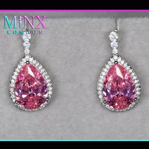 Könnte beinhalten: Ein Paar silberne Tropfenohrringe mit einem rosa birnenförmigen Stein, der von einem Heiligenschein aus kleineren klaren Steinen umgeben ist.