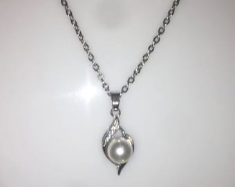May include: A silver chain necklace with a pendant featuring a single white pearl set in a silver swirl design.