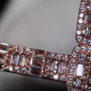May include: A rose gold band ring with a row of baguette-cut diamonds set in a pave setting.
