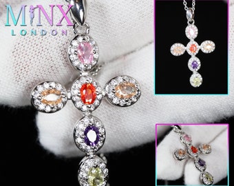 Puede incluir: Colgante de cruz de plata con un halo de piedras transparentes alrededor de cada una de las siete piedras preciosas de colores. Las piedras preciosas son rosa, naranja, amarilla, verde, morada y dos tonos de naranja.