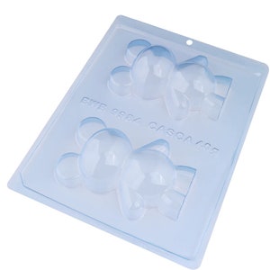 May include: A clear plastic mold for making chocolate bears. The mold has two cavities, each shaped like a bear. The mold is labeled "RWB 8884 CASCA 408".
