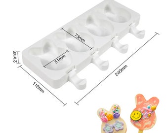 May include: White silicone mould with four bunny-shaped cavities for making popsicles. The mould measures 24 cm long, 11.2 cm wide, and 6.5 cm tall. The mould has a handle on each cavity for easy removal of the popsicles.
