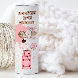 May include: A pink and white travel tumbler with the words "TRAVEL THE WORLD" in black letters. The tumbler features a globe, a map, a suitcase, and a neck pillow.
