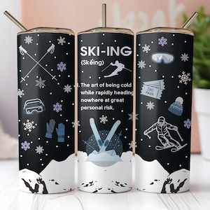 May include: A black and white tumbler with a winter sports theme. The tumbler features a skier, ski poles, snowflakes, and the text "SKI-ING (Skeing) The art of being cold while rapidly heading nowhere at great personal risk."