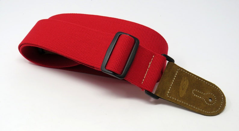 May include: Red guitar strap with a black buckle and a brown suede end piece with a guitar keyhole.