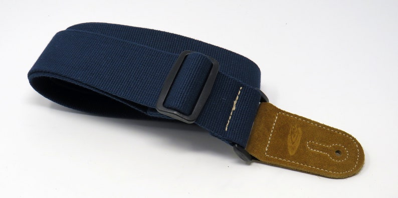 May include: A dark blue guitar strap with a brown leather end and a black metal buckle.