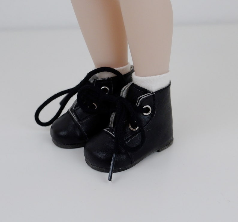 May include: A pair of black leather lace-up boots with white laces. The boots have a rounded toe and a low heel.