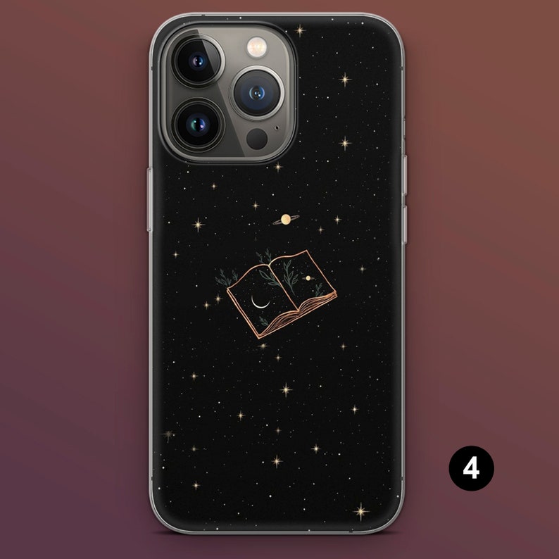 Puede incluir: Funda de tel&eacute;fono negra con dise&ntilde;o de noche estrellada. La funda presenta un contorno dorado de un libro abierto con una luna creciente e ilustraciones de plantas. Tambi&eacute;n se representa un planeta y estrellas.