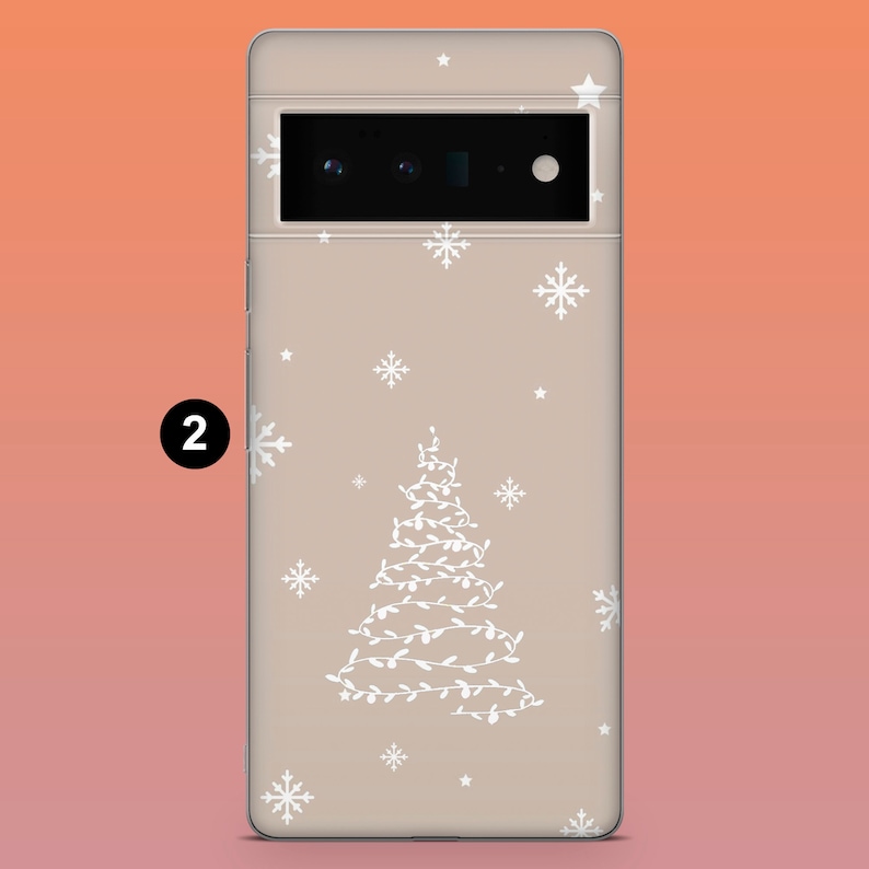 Puede incluir: Una funda de tel&eacute;fono con un dise&ntilde;o festivo. La funda es de color beige claro y presenta un &aacute;rbol de Navidad blanco hecho de luces, junto con copos de nieve y estrellas blancos. La funda tiene un recorte para la c&aacute;mara y el n&uacute;mero "2" en un c&iacute;rculo negro.