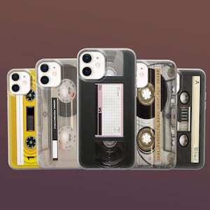 May include: A collection of five phone cases featuring retro cassette tape and VHS tape designs. The cases showcase various colors and details, including labels and tape mechanisms. The cases are arranged in a row against a dark brown background.