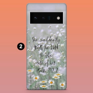 May include: A phone case featuring a floral design with white daisies and green stems. The case has the text "She confidently trusts the Lord to take care of her. Psalm 112:7" in a handwritten style.