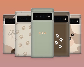Puede incluir: Una colección de fundas para teléfonos con varios diseños. Las fundas presentan huellas de patas, formas abstractas e ilustraciones de cachorros. La paleta de colores incluye tonos beige, marrón y verde, con una funda de color sólido en el centro.