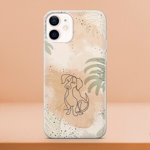 May include: Clear phone case featuring a line drawing of a dog. The design includes watercolor-style beige and brown background with green and white leaf accents. Black speckles add detail to the design.