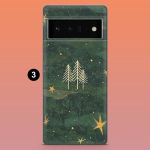 Puede incluir: Una funda de tel&eacute;fono con fondo verde oscuro, con un dise&ntilde;o de estrellas doradas y tres pinos dorados. La funda tiene un aspecto texturizado y un recorte para la c&aacute;mara en la parte superior.