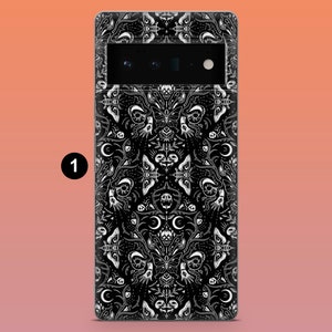 May include: Black phone case with a white gothic pattern featuring moths, skulls, and crescent moons. The case has a camera cutout and a black border. The design is symmetrical and detailed.