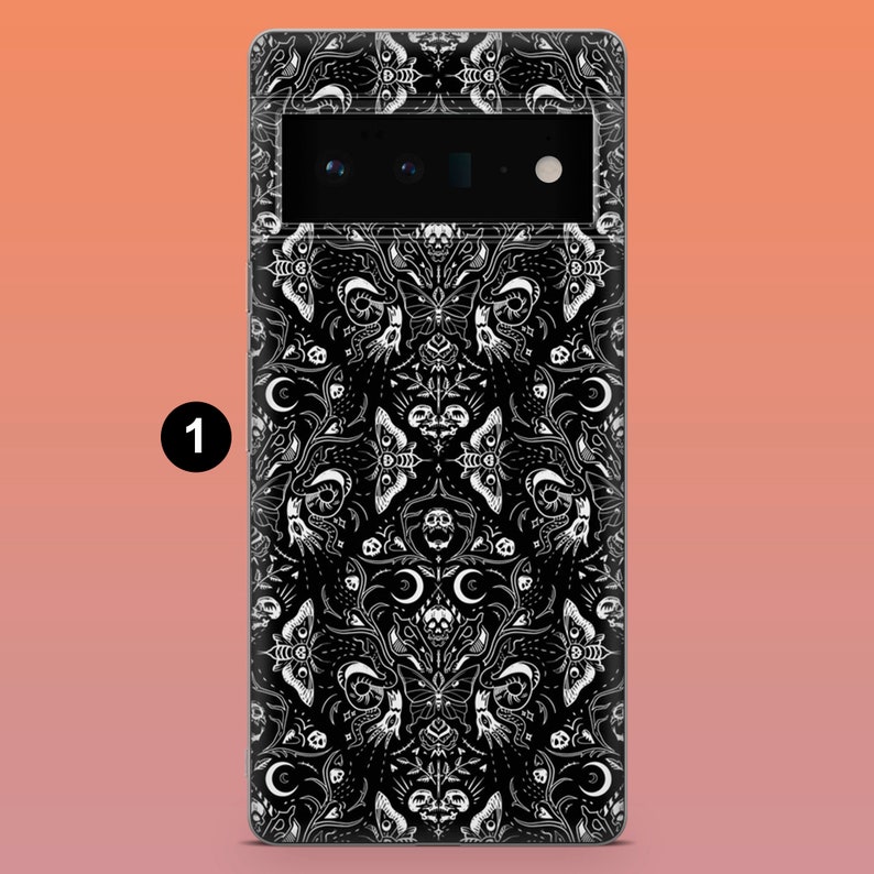 May include: Black phone case with a white gothic pattern featuring moths, skulls, and crescent moons. The case has a camera cutout and a black border. The design is symmetrical and detailed.