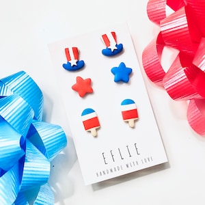 May include: A set of six red, white, and blue polymer clay earrings. The earrings are shaped like stars, ice cream cones, and top hats. The card reads "EFFIE HANDMADE WITH LOVE".