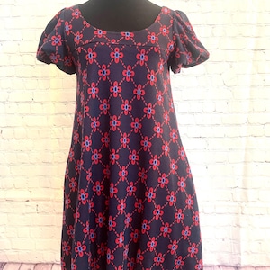 May include: A navy blue dress with a red and blue floral pattern. The dress has short puff sleeves and a scoop neckline.