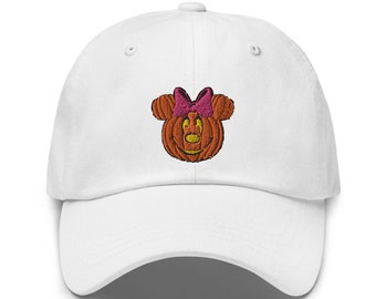 May include: White baseball cap with an embroidered pumpkin design. The pumpkin is orange with a smiling face and a pink bow. The cap has a curved brim and an adjustable strap.