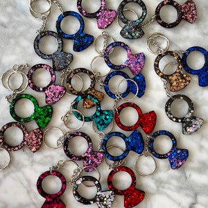May include: A collection of colorful, sparkly keychains shaped like rings. Each keychain features a different color and glitter pattern.