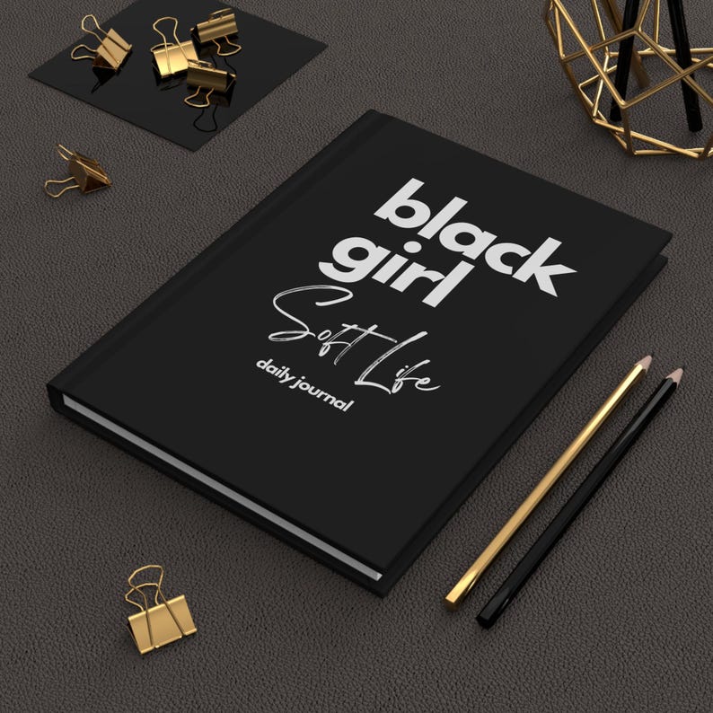 May include: Black journal with the text "black girl soft life" and "daily journal" in white lettering.