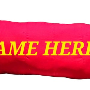 May include: A red rectangular pillow with yellow text that reads "NAME HERE".