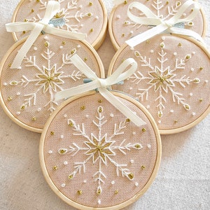 Christmas ornaments in a lovely snowflake design embroidered with white and gold thread on fine greek cotton fabric set on a 3.5 inches bamboo hoop. They come with a white bow and ribbon to hang and gift-wrapped in a beautiful box with ivory ribbon