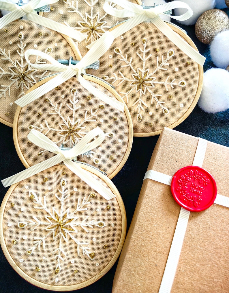 Christmas ornaments in a lovely snowflake design embroidered with white and gold thread on fine greek cotton fabric set on a 3.5 inches bamboo hoop. They come with a white bow and ribbon to hang and gift-wrapped in a beautiful box with ivory ribbon