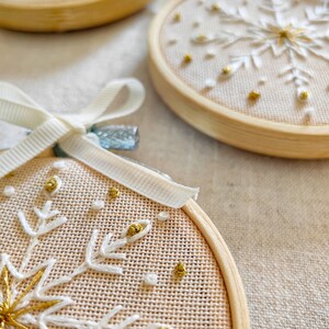 Christmas ornaments in a lovely snowflake design embroidered with white and gold thread on fine greek cotton fabric set on a 3.5 inches bamboo hoop. They come with a white bow and ribbon to hang and gift-wrapped in a beautiful box with ivory ribbon