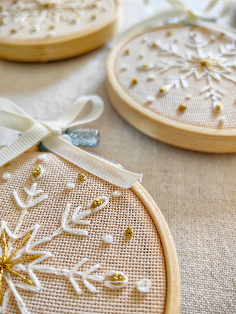 Christmas ornaments in a lovely snowflake design embroidered with white and gold thread on fine greek cotton fabric set on a 3.5 inches bamboo hoop. They come with a white bow and ribbon to hang and gift-wrapped in a beautiful box with ivory ribbon