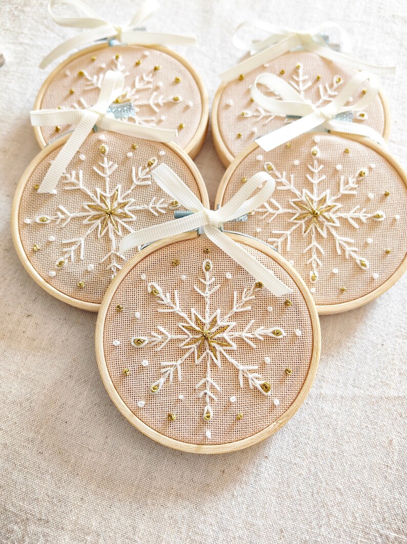 Christmas ornaments in a lovely snowflake design embroidered with white and gold thread on fine greek cotton fabric set on a 3.5 inches bamboo hoop. They come with a white bow and ribbon to hang and gift-wrapped in a beautiful box with ivory ribbon