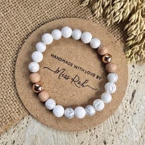 May include: White and brown beaded bracelet with rose gold accents. The bracelet is on a brown background with the text "Handmade with love by Miss Roh".